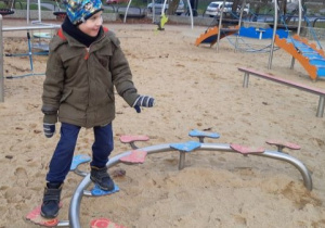 Chłopiec na równoważni na placu zabaw.